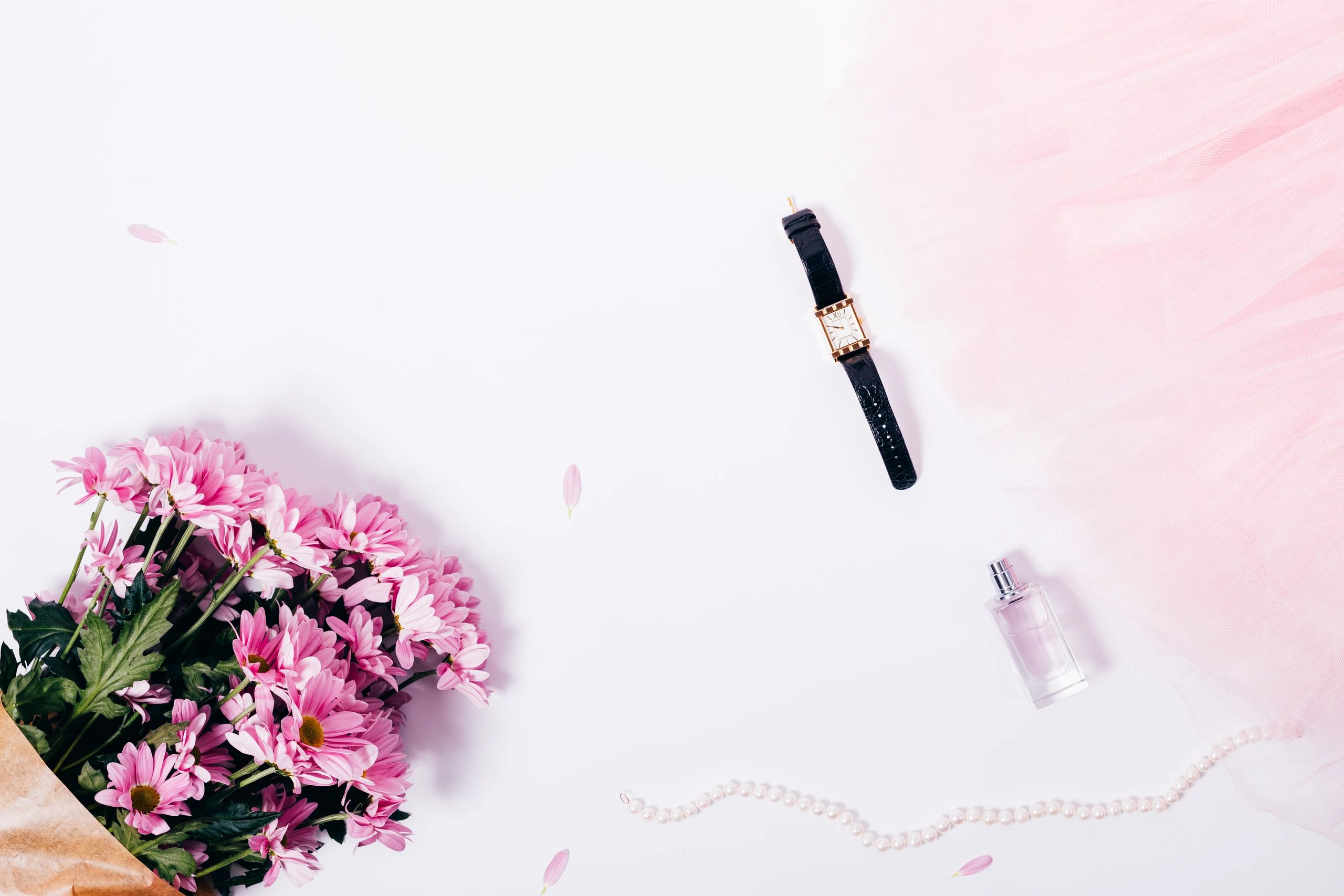 Feminine fashion flat lay with flowers, accessories, and soft pink styling